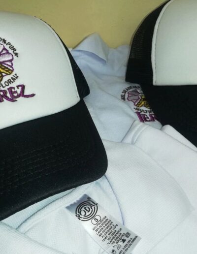 Gorras de camionero blancas y negras con bordado 'Miel de Abejas Multifloral Jerez', diseño de abeja y flor.