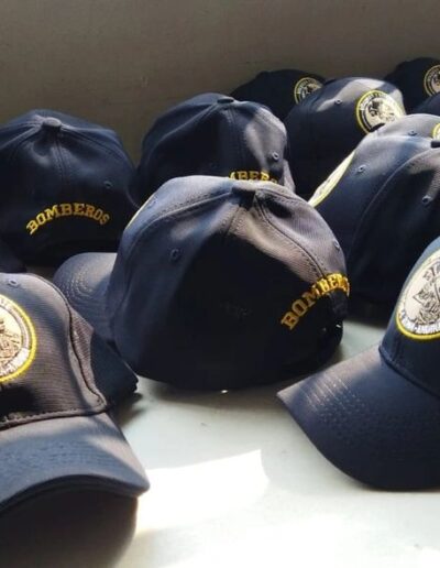 Gorras azul oscuro bordadas para bomberos con logo y texto 'BOMBEROS' en hilo dorado y escudo