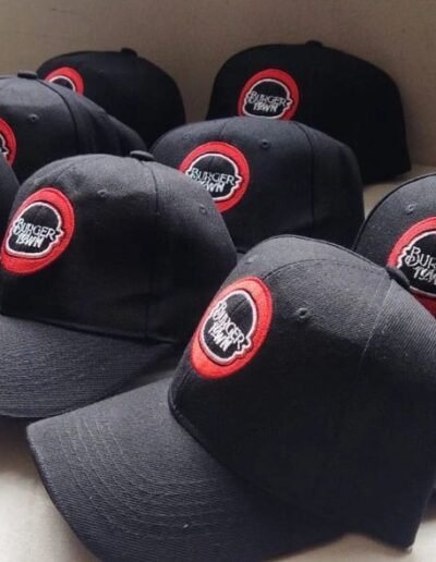 Gorras negras con logo bordado 'Burger Town' en círculo rojo para personal de restaurante.